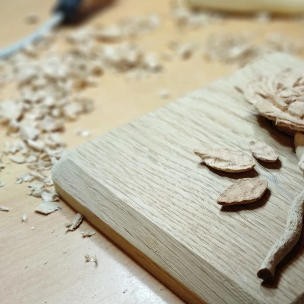 Wooden ashes casket work in progress with oak leaf and nut carving on lid and wood shavings in background.